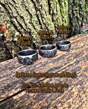Three textured metal rings displayed on a weathered log in front of tree bark, with overlaid text showing ring options: Option 1 Crater, Option 2 Timber, Option 3 Cascade, and text noting optional engraving on all rings.