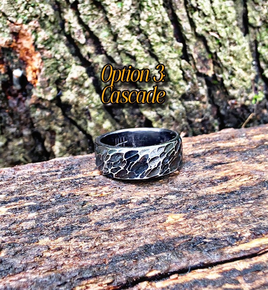 A silver ring with a textured, crackled pattern sits on a weathered log outdoors, with a tree trunk in the background. The text 'Option 3: Cascade' is overlaid near the top.