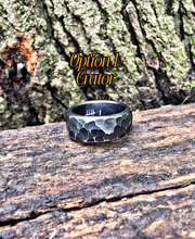 A hammered metal ring with a dark interior and white engraved tally marks sits on a weathered log outdoors, with bark in the background and the text 'Option 1: Gator' overlaid near the top.